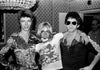 A black and white photograph featuring David Bowie, Iggy Pop, and Lou Reed, with a signature stamp and the Mick Rock Estate logo.