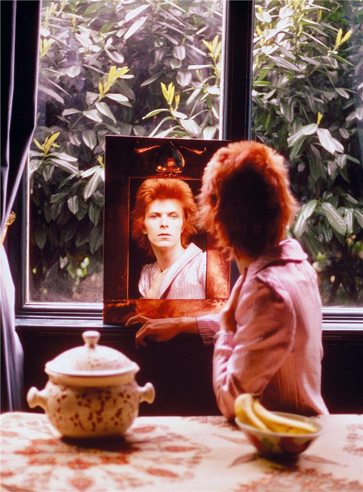 A limited edition fine art photograph of David Bowie, known as Ziggy Stardust by a window looking in a mirror. The image was shot by Mick Rock. 