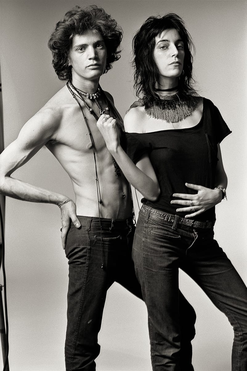 Black and white photo of Patti Smith and Robert Mapplethorpe posing against a plain background