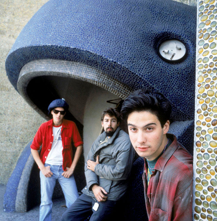A black and white photograph of three members of the Beastie Boys, standing in front of a decorative wall.
