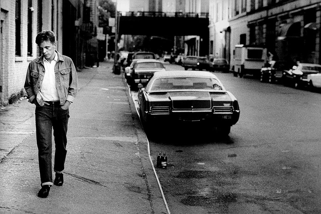 Bernard Sumner of New Order walking in New York City, 1983, captured by photographer Kevin Cummins.
