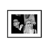 a framed black and white photo of bono of U2 and lady gaga. he is holding forks over her eyes. shot by photographer Mick Rock. 