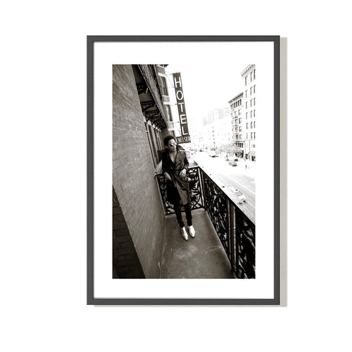 Black and white fine art photograph framed of Lenny Kravitz standing on a balcony, embossed with 'Mick Rock' signature stamp.