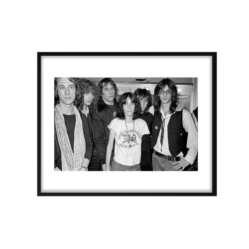 A black and white framed photograph of Patti Smith with John Cale, featuring them both in the foreground with other band members in the background.