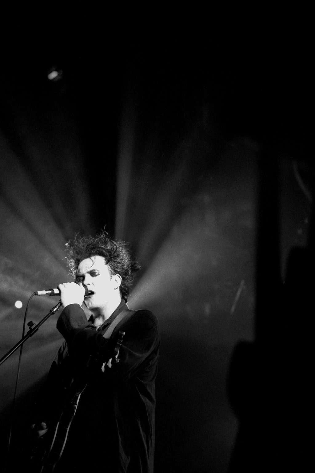 Robert Smith of The Cure performing live on stage in 1992, captured by photographer Kevin Cummins.
