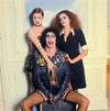 Tim Curry sitting and girls around him. Cast of The Rocky Horror Picture Show. Photographed y Mick Rock. 