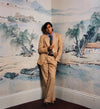 A fine art photograph of Bryan Ferry, in a contemplative pose with a blurred background featuring a landscape or architectural detail. Shot by Mick Rock. 